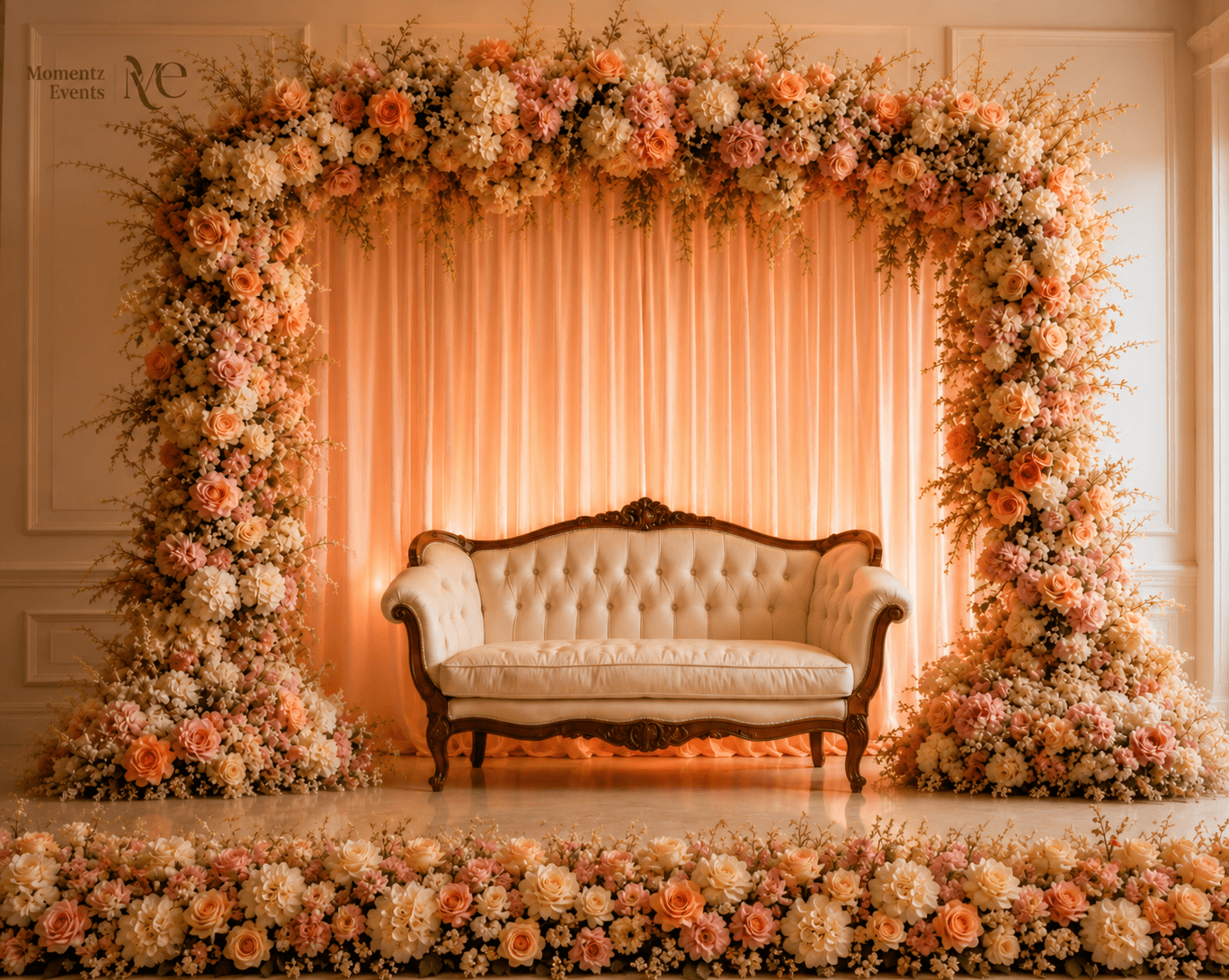 Peach and cream floral arch backdrop with a loveseat, styled by Momentz Events