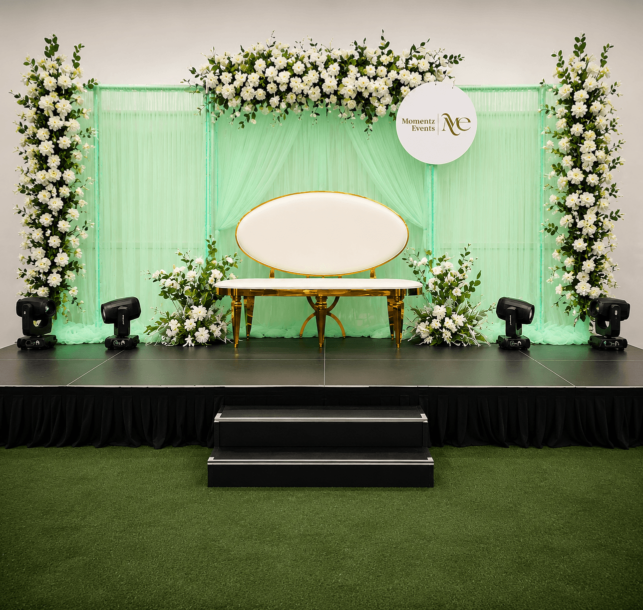 Elegant mint green draped stage with a gold loveseat and floral pillars, styled by Momentz Events